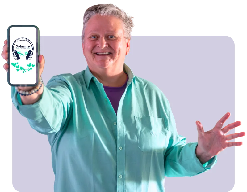 The photo shows a smiling person wearing a turquoise shirt, holding a phone displaying a logo with “Jolanne” and headphones surrounded by green hearts.